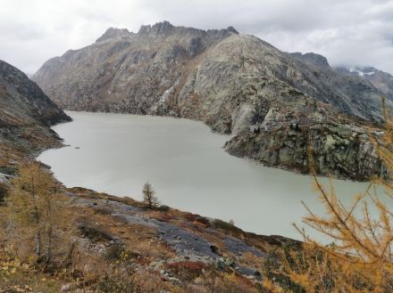 Ein See in einem Bergtal, der Himmel bewölkt.