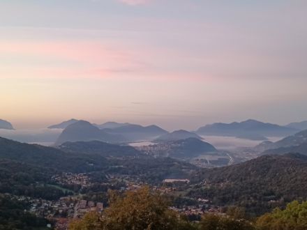 Morgenstimmung über der Region Lugano. Über dem Lago di Lugano liegen einige Nebelfelder. Der Himmel darüber ist mit dünnen hohen Wolkenfeldern überzogen.