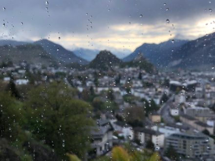 Wassertropfen an einer Scheibe, die natürlich wiederum eine andere Form haben als wenn sie in der Luft sind. Im Hintergrund die Stadt Sion. 