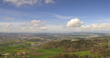 Flache, kleine Quellwolken über Hügel und Ortschaften.
