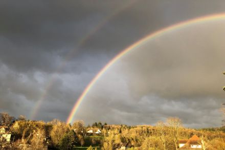 Doppelter Regenbogen vor schwarzen Wolken.