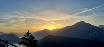 Sonnenaufgang über Bergen, Himmel ist geld-orange verfärbt.