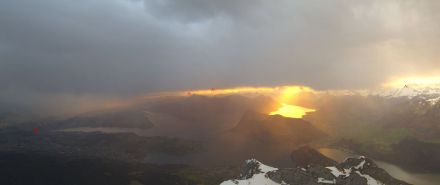 Webcambild Pilatus am Morgen. Das Gersauerbecken im feurigen Morgenrot. Der Regen erfasste die Zentralschweiz pünktlich zu Tagesbeginn. 