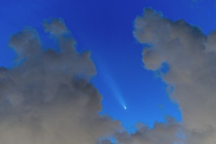 Komet am blauen Abendhimmel zwischen grauen Wolken.
