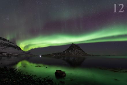 Grüne Polarlichter über dem isländischen Berg Kirkjufell mit Spiegelung im Wasser des Fjords auf der Halbinsel Snaefellsnes im März 2024. (L. Peyraud)