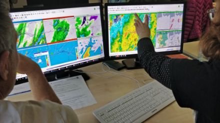 Visualisierung einer Kollegin des Deutschen Wetterdienstes. Auf dem linken Bildschirm sind Modelldaten zu sehen, auf dem rechten eine Radaranimation und Flugwetterprodukte.