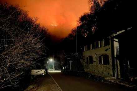 Foto in der Nacht mit Blick in ein Tal, im Hintergrund brennt der Wald.