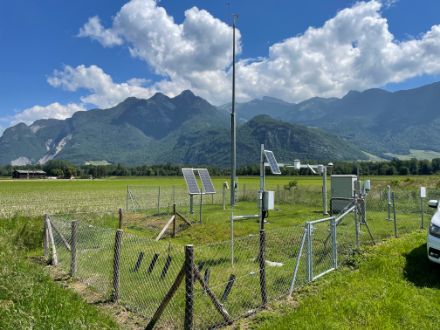 Messstation auf einer Wiese mit Bergen im Hintergrund.