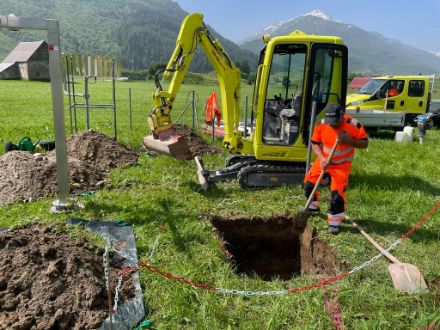 Bauarbeiter gräbt Loch mit Minibagger und Schaufel.