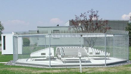 Die Antennen in der Bildmitte in Form weisser, parallel angeordneter Röhren, umgeben von einem zwei Meter hohen Zaun aus Metall.