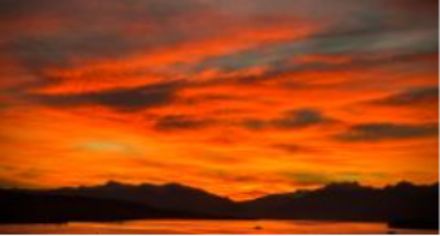 Morgenrot an einem See und im Hintergrund Berge.