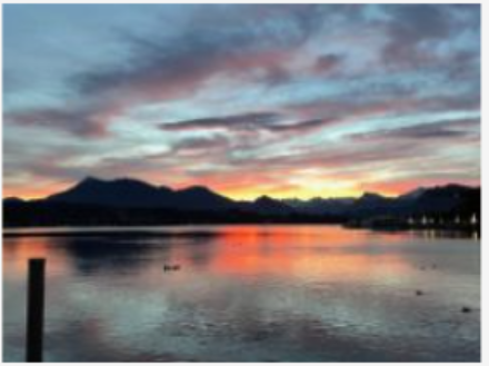 Sonnenaufgang mit Bergen und See.