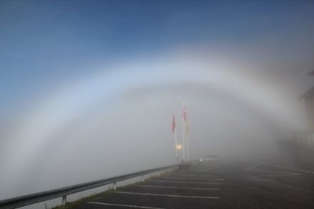 Bild eines weiss leuchtenden Nebelbogens. Oberhalb des Nebelbogens ist der wolkenlose Himmel zu sehen.
