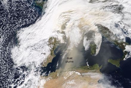 Satellitenbild von Nordafrika und Europa. Über dem Mittelmeer ist eine hellgelbe Staubwolke zu erkennen.
