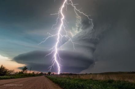  	Bild einer rotierenden Gewitterwolke und einem Blitzeinschlag über einer ebenen Landschaft. 