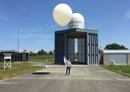 Auf dem Bild hält ein Mann eine Schnur in der Hand, an der ein Wetterballon schwebt.