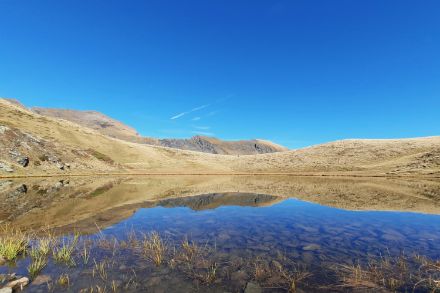 Bergsee mit Bergspiegelung und blauem Himmel.