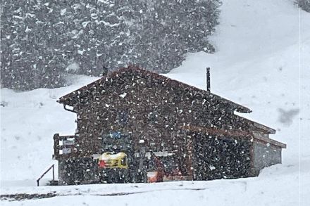 Schneeflocken vor einem Holzhaus