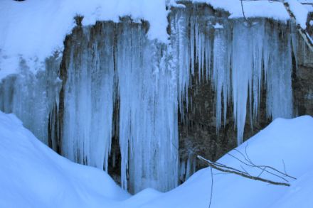 Lange Eiszapfen an einer Felswand.