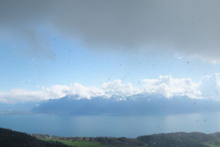 Schneefall und frühsommerlich anmutende Quellwolken in einem Bild vereint (MeteoSchweiz-Wetterkamera Mont Pèlerin oberhalb von Vevey, 7. April 2023).