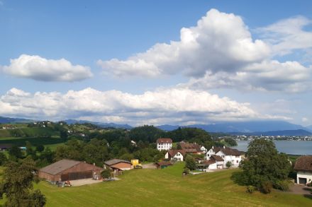 Landschaft mit Häusern und blauem Himmel mit Wolken