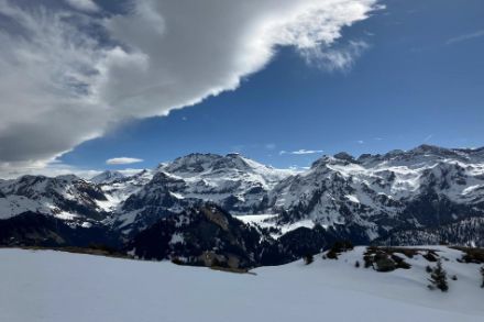 Gebirgslandschaft mit Schnee, blauem Himmel und Föhnwolken