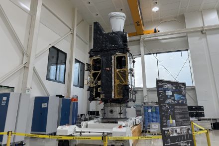 Der Meteosat Third Generation Sounder (MTG-S) Satellit steht in einem Reinraum während der Integrations- oder Testphase. Er steht auf einer Transportplattform, umgeben von Sicherheitsabsperrungen und Informationsmaterial.